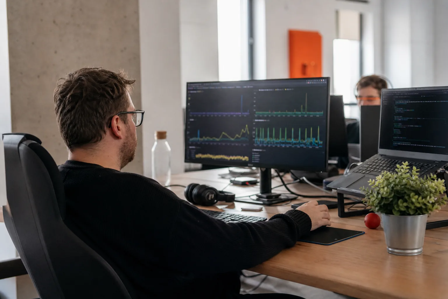 Programista sprawdza wykresy dostępności systemu na monitorze w spokojnym biurze technicznym